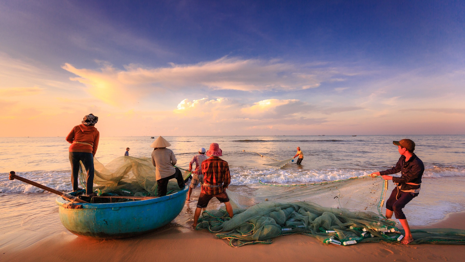 local fishermen on the beach in Hoi An pulling their fishing nets